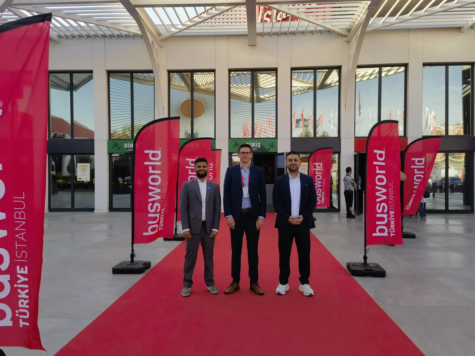 Three team members on the red carpet outside the Busworld Türkiye venue in Istanbul